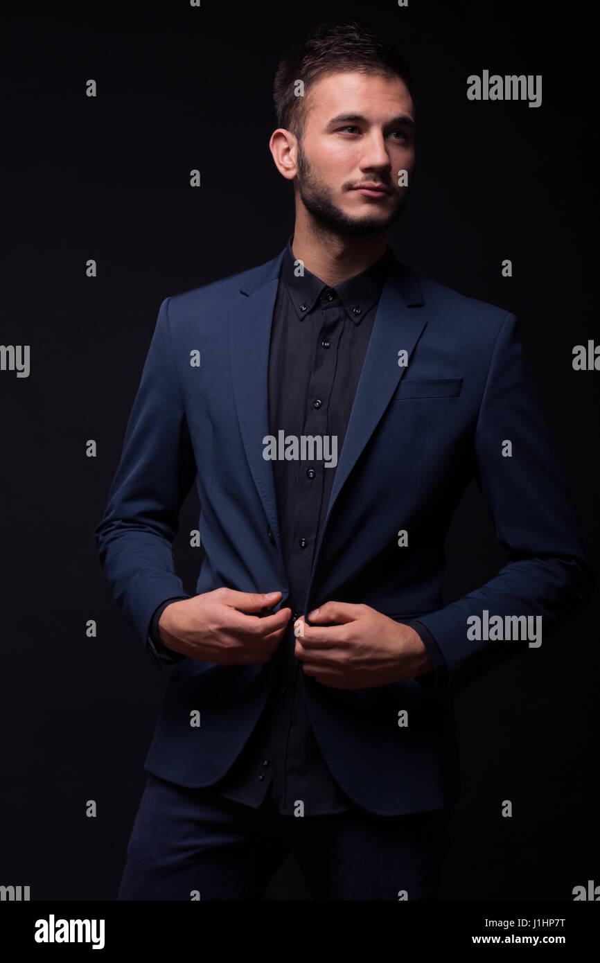 Giovane uomo, abbottonatura camicia, vestiti scuri, indossa una giacca blu  tuta pantaloni e camicia nera Foto stock - Alamy