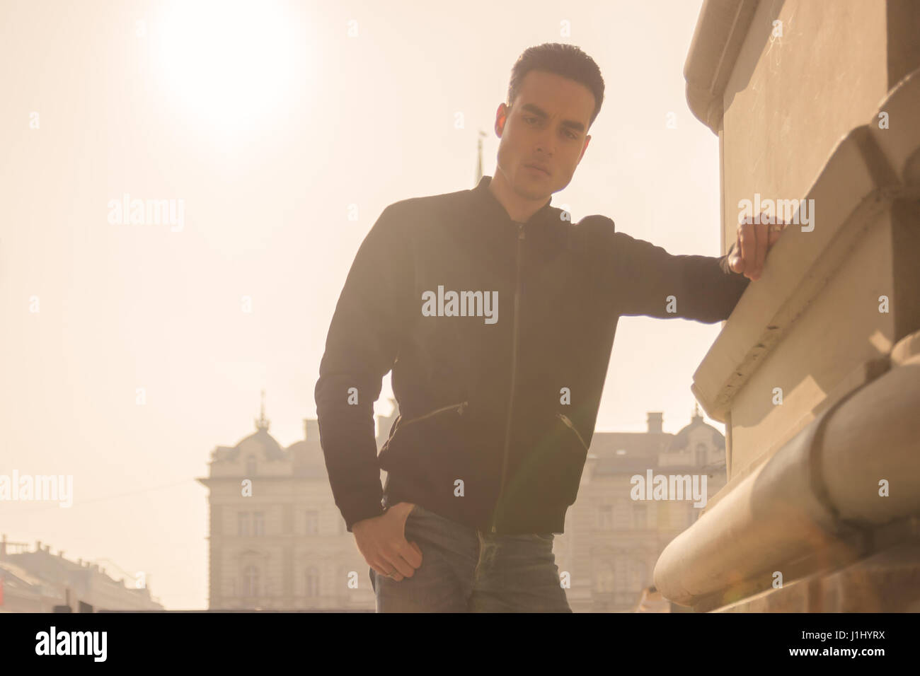 Un giovane uomo adulto solo, forte abbagliamento daylight Sun giornata soleggiata all'aperto città ritratto, giallo arancio il colore del cielo Foto Stock