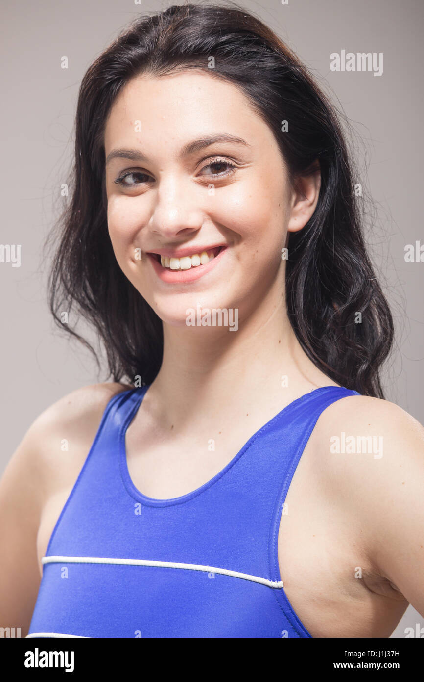 Closeup faccia di testa, una giovane donna sorridente nuotatore costume da bagno e sfondo grigio Foto Stock