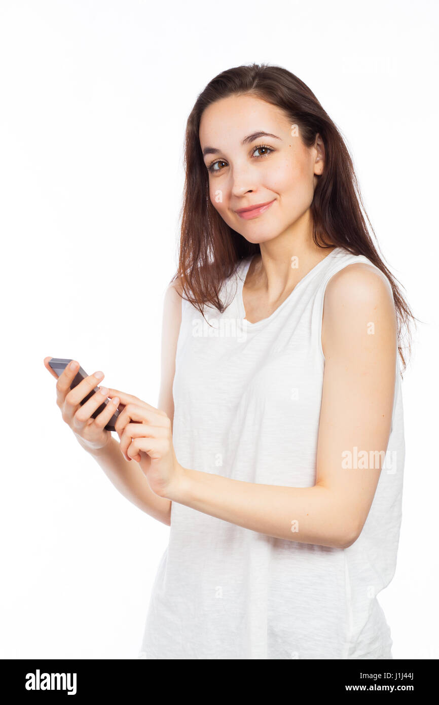 Giovane donna utilizzando un telefono e guardando la telecamera, isolato su bianco Foto Stock