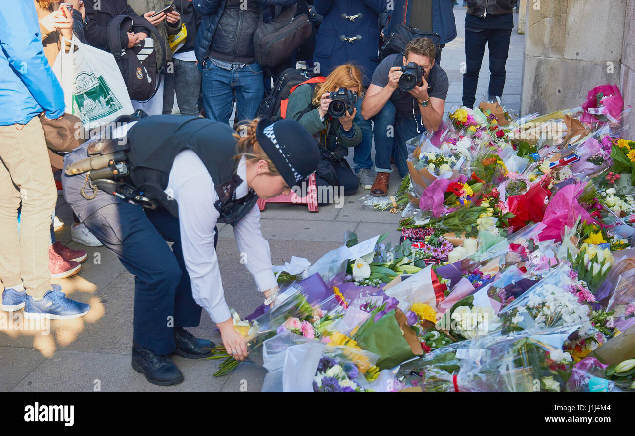 Poliziotta portando fiori per le vittime della Westminster attacco terroristico a Londra, Inghilterra Foto Stock