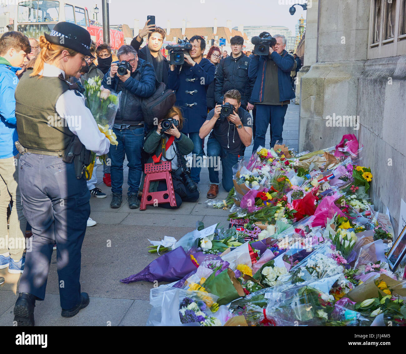 Poliziotta portando fiori per le vittime della Westminster attacco terroristico a Londra, Inghilterra Foto Stock