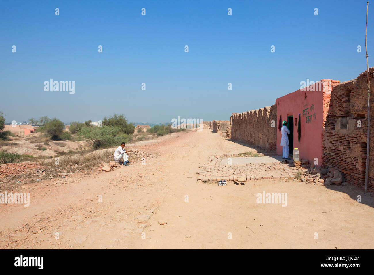 Un piccolo tempio indù dipinta in rosa con le persone e con le scarpe fuori sul bhatner fort complesso nella città hanumangarh attualmente in fase di restauro con acacia s Foto Stock