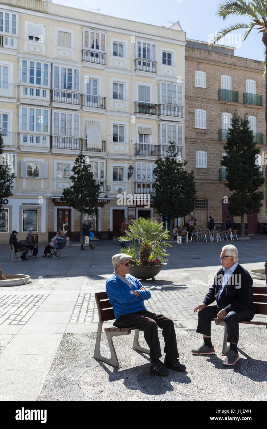 Anziani parlare seduto su una panchina con tranquillità in una splendida piazza di Cadice, Andalusia, Spagna Foto Stock