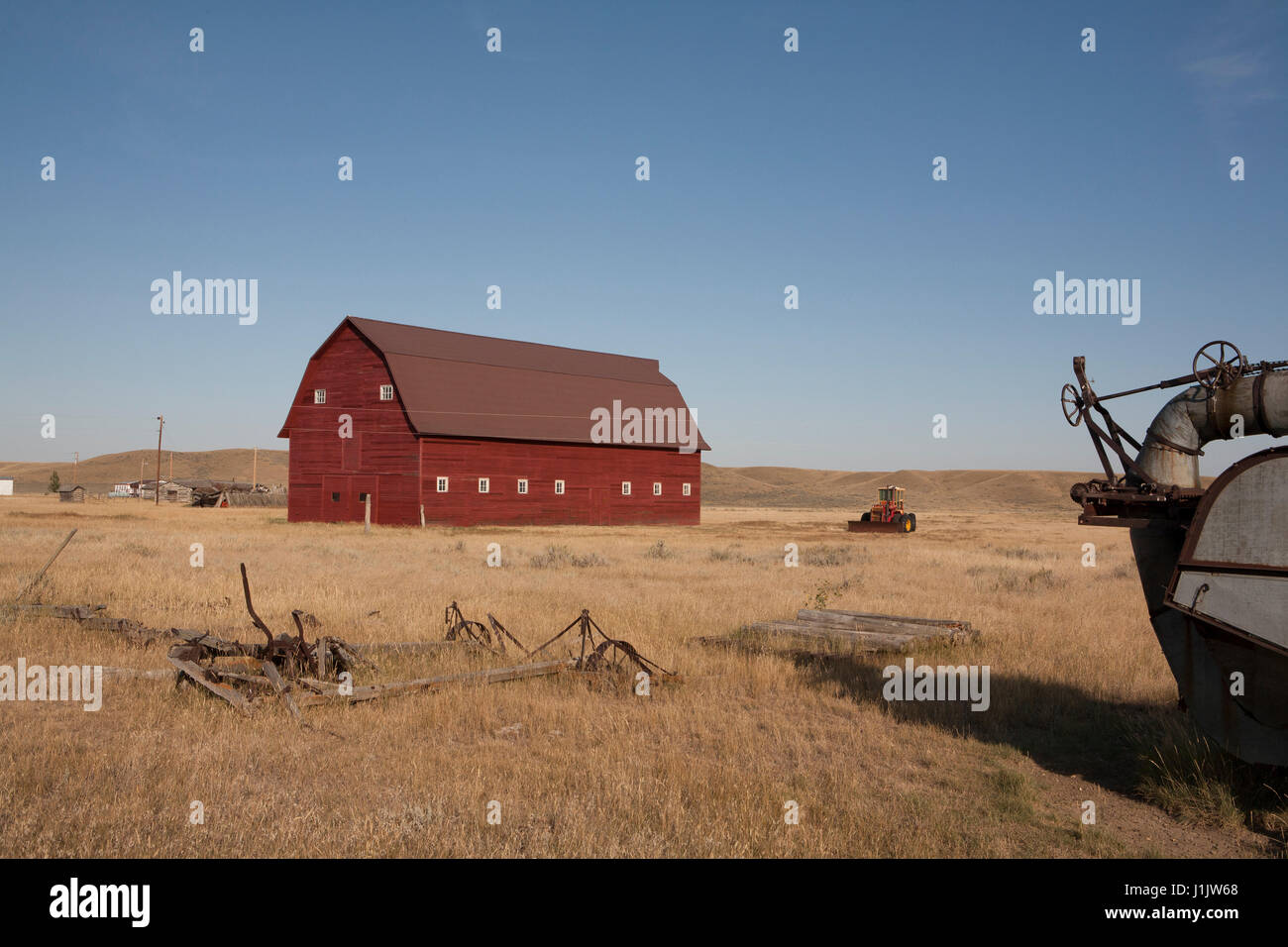 Parzialmente ristrutturato 1928 granaio sulla Joe Hartman Ranch. Abbandonata la mietitrebbia e harrow fornire framing di primo piano di questo montana orientale foto. Foto Stock