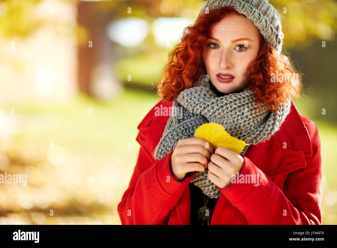 Malinconica ragazza di zenzero in autunno con foglie di colore giallo Foto Stock