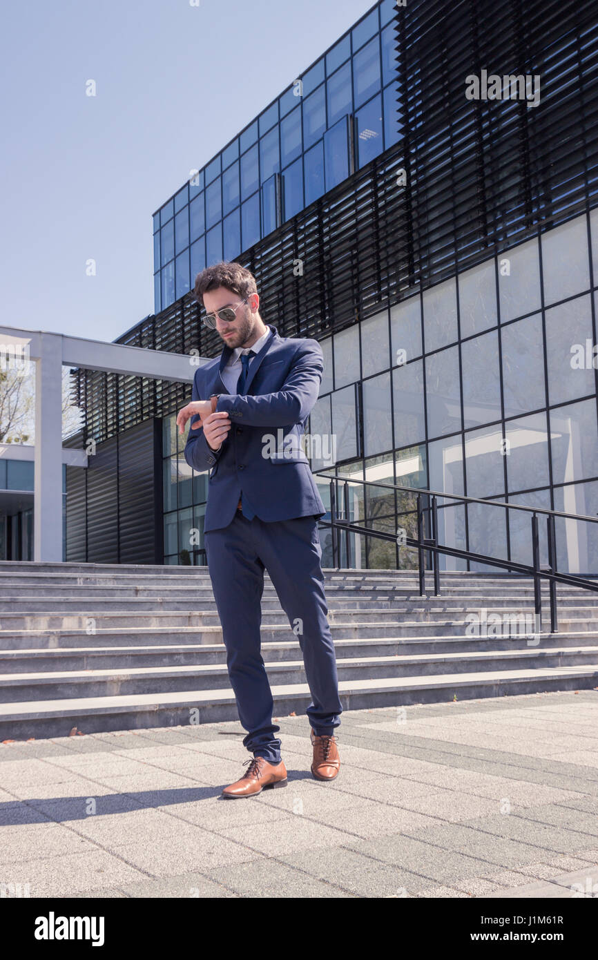 Un giovane uomo, cercando di guardare, formale abbigliamento moderno, suit tie, edificio di architettura, all'aperto giorno Foto Stock