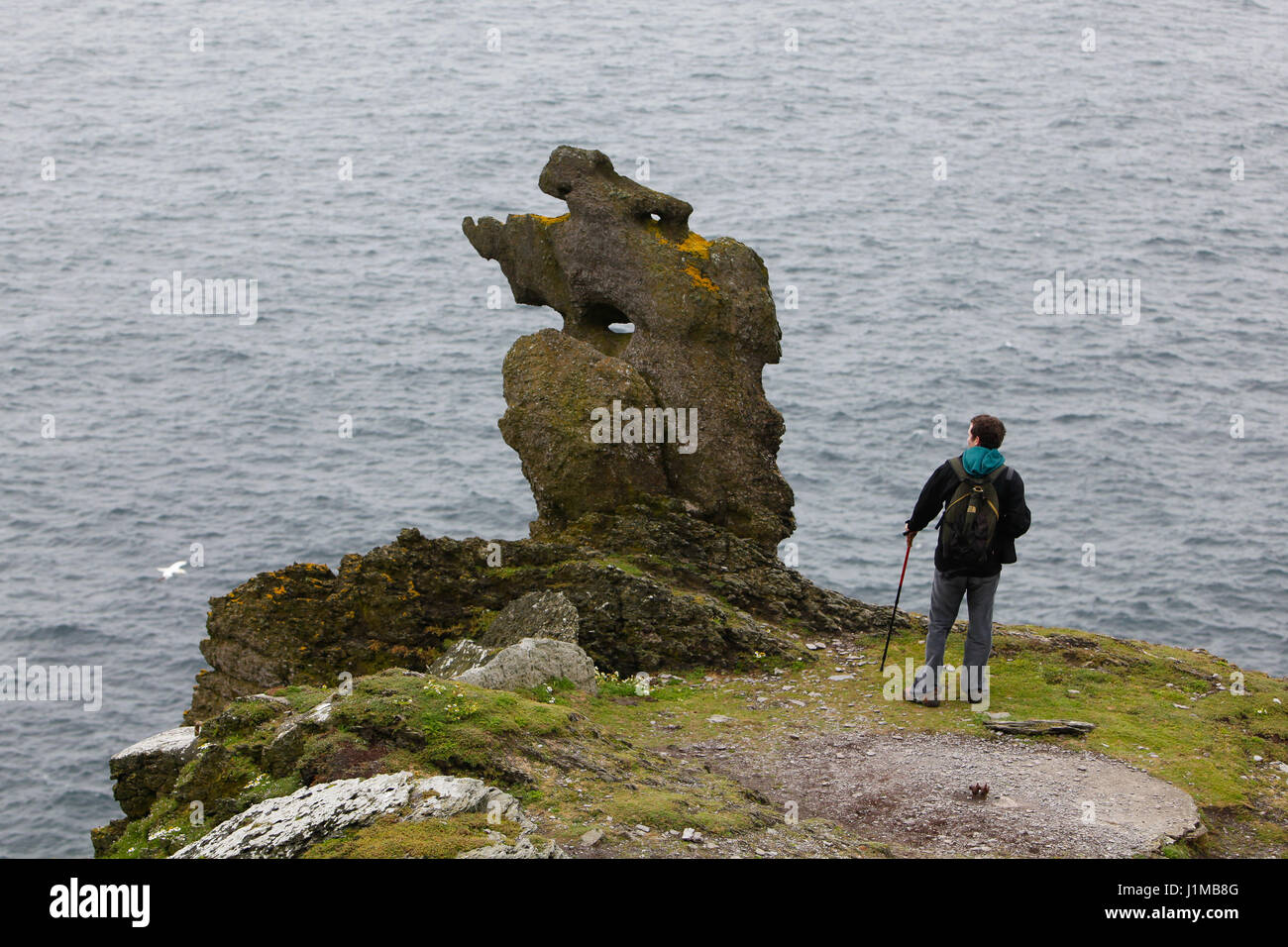 Un uomo guarda ad un insolito rock su Skellig Michael. Foto Stock