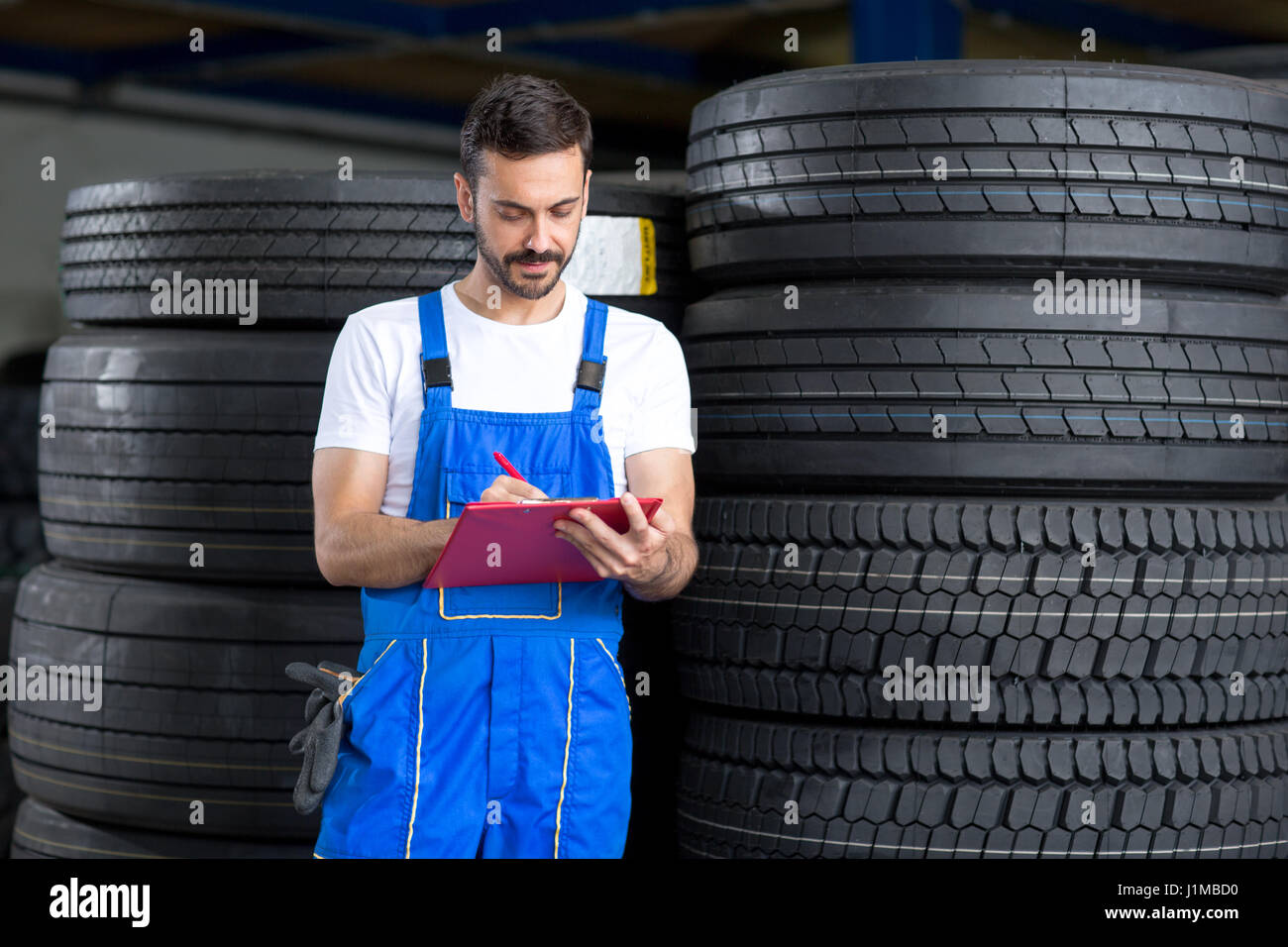 Mechanic scrive negli appunti nel negozio del pneumatico Foto Stock