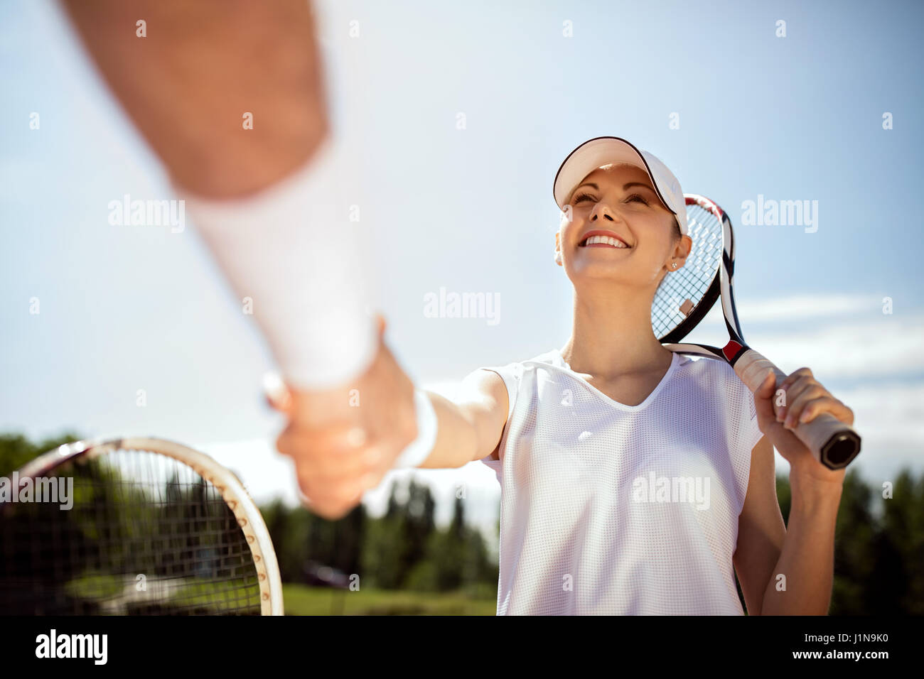 Soddisfatto femmina giovane giocatore di tennis saluta con trainer sul campo da tennis Foto Stock