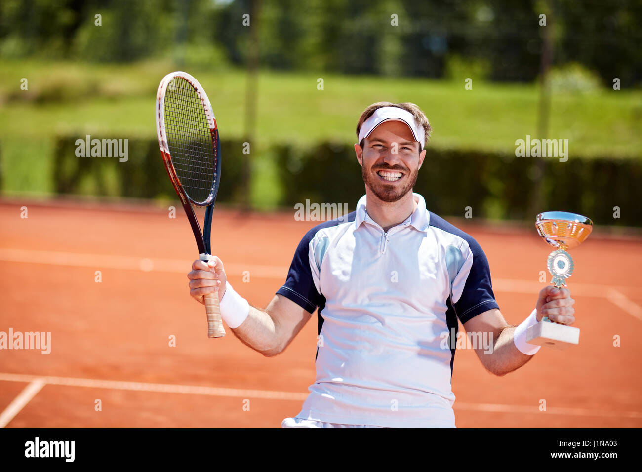 Vincitore del maschio nel match di tennis con la coppa del vincitore e racket Foto Stock