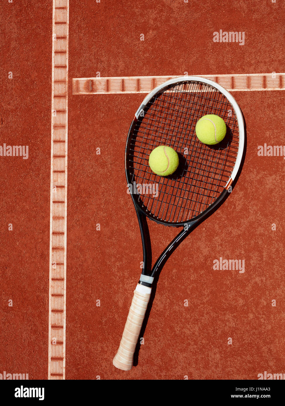 Close up della racchetta da tennis e palle gialle in argilla rossa sul campo da tennis Foto Stock