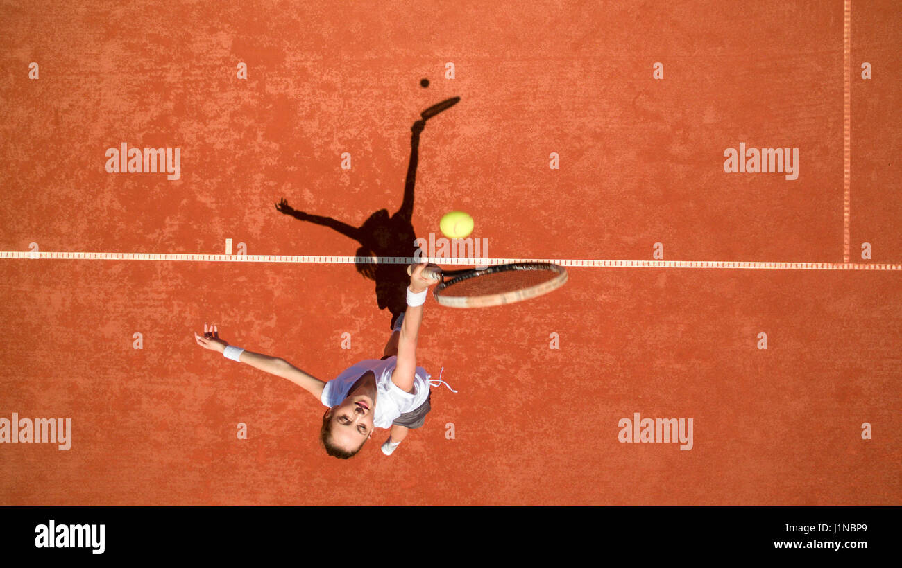 Femmina giovane giocatore di tennis di colpire la sfera gialla sul terreno di tennis Foto Stock