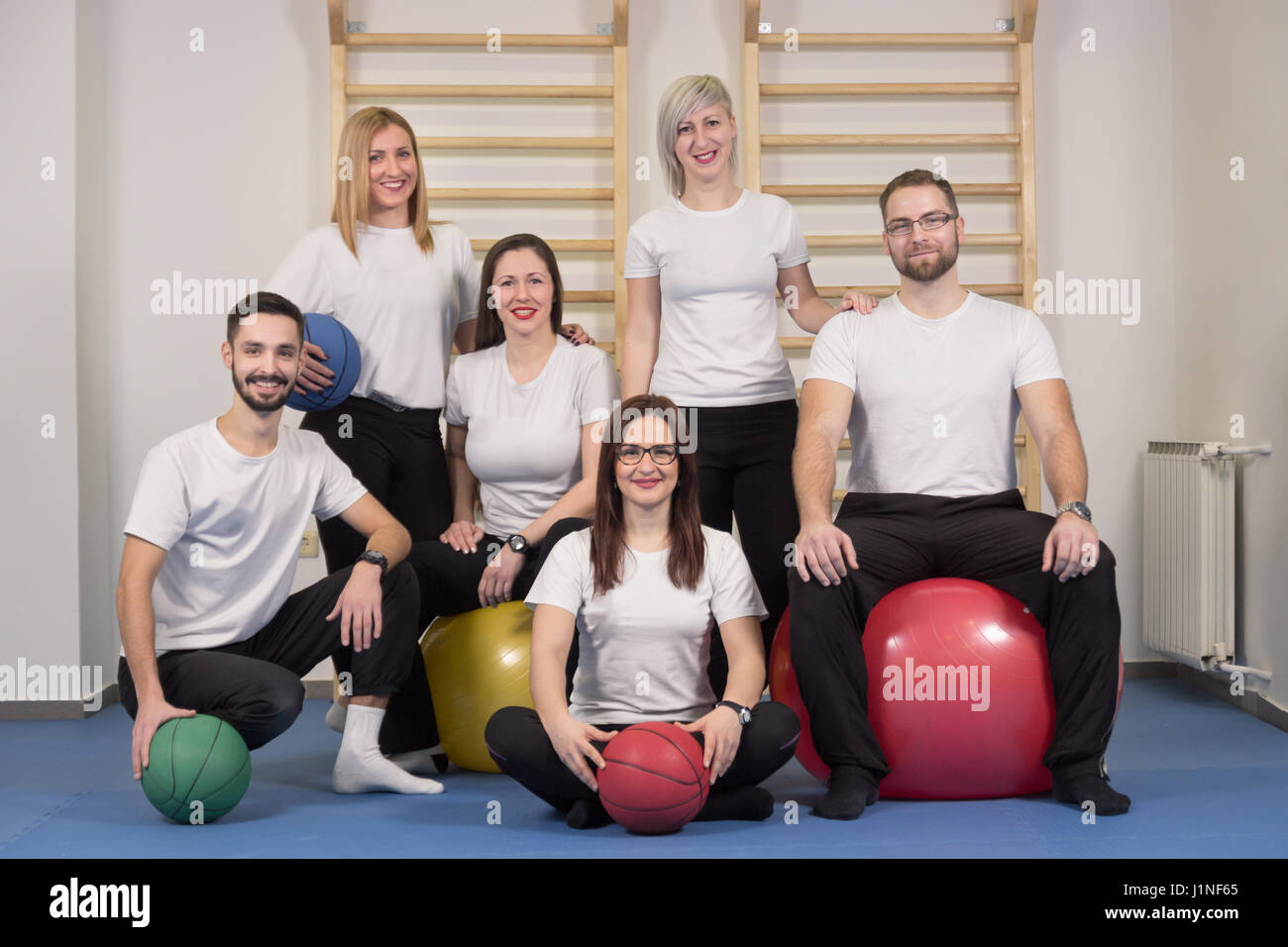 Grande gruppo di persone, fisioterapisti chiropratici, interni ritratto, seduto in piedi, palle ginniche Foto Stock