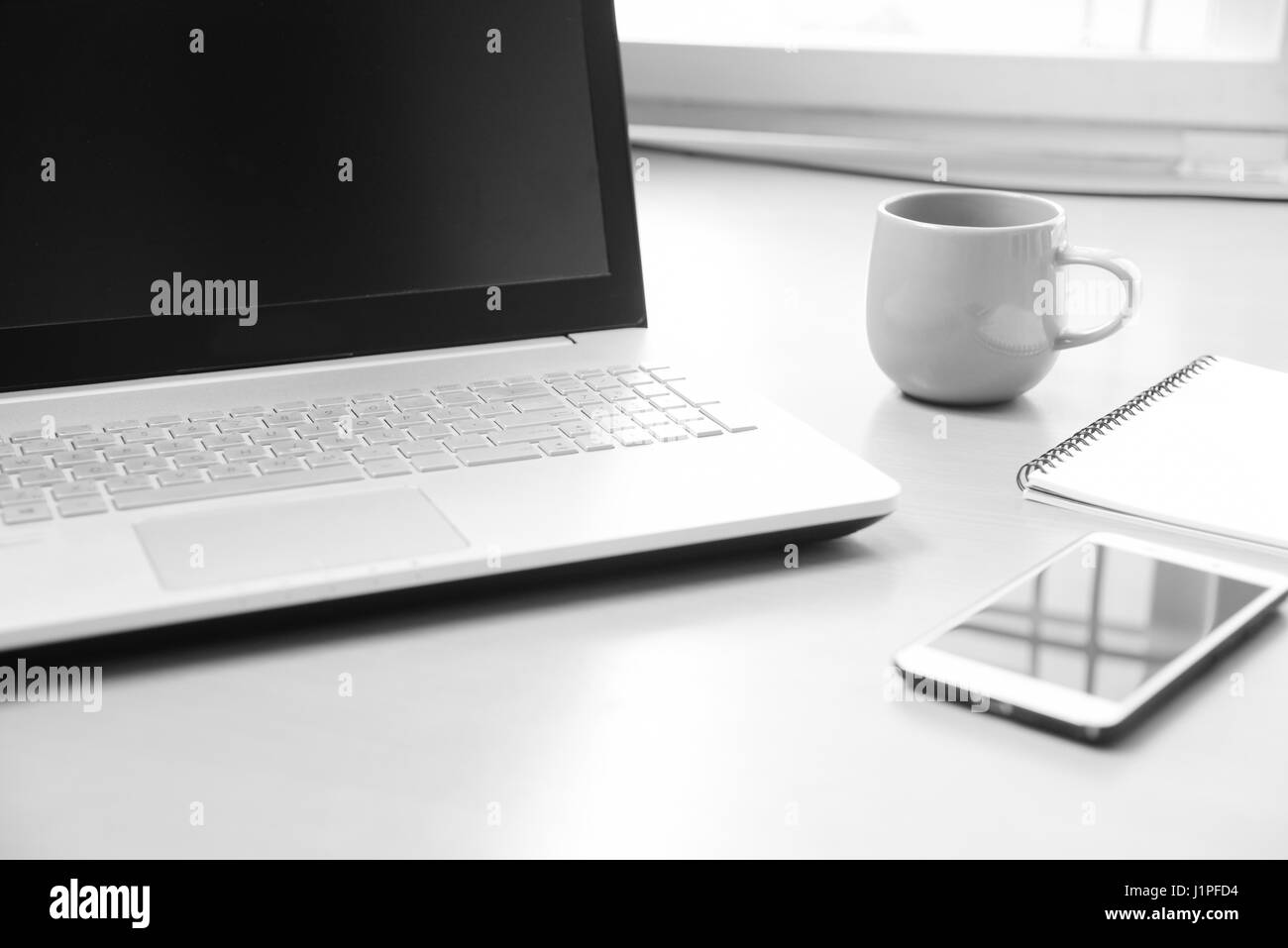 Business notebook computer con smart phone , quaderno per gli appunti messaggio e una tazza di caffè sulla scrivania di legno sfondo ( soft focus in bianco e nero Foto Stock