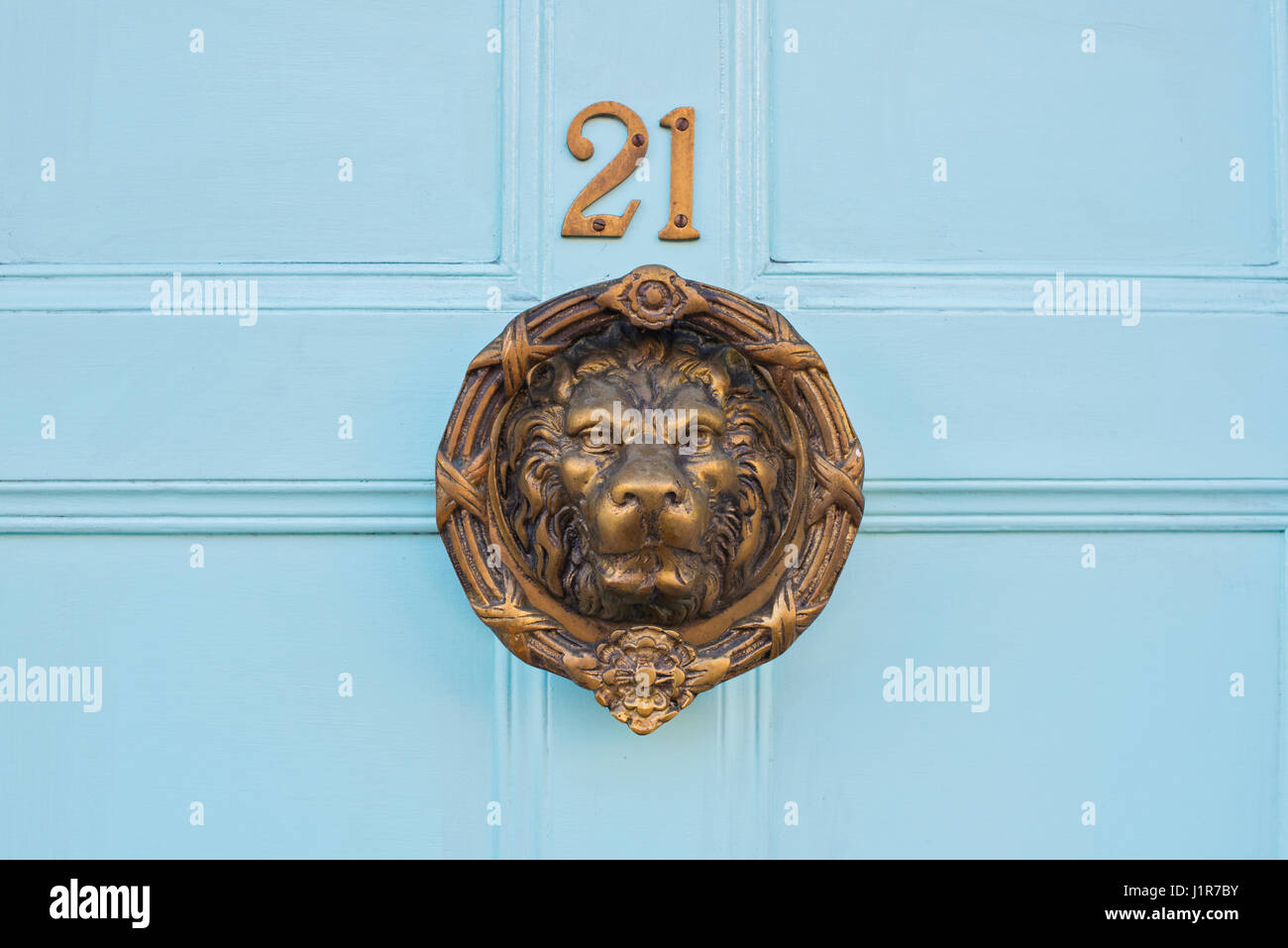 Ottone Lions Head porta respingente e 21 numero di casa su un blu porta in legno. Warwick Warwickshire, Inghilterra Foto Stock