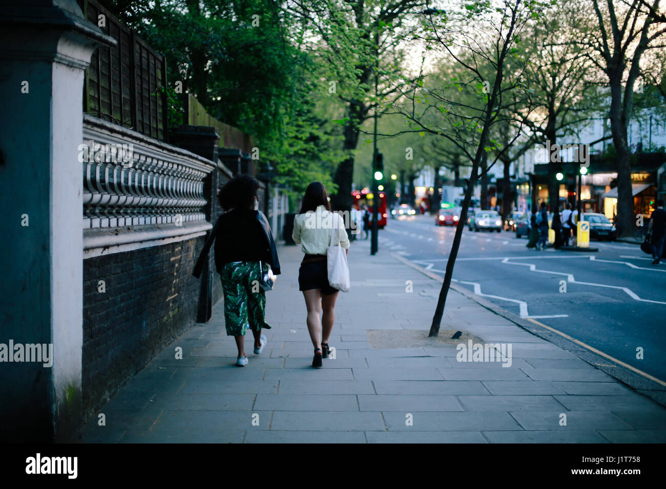 Le donne di camminare sulla strada di Londra nel tramonto su dei più caldi durante i fine settimana di aprile. Foto Stock