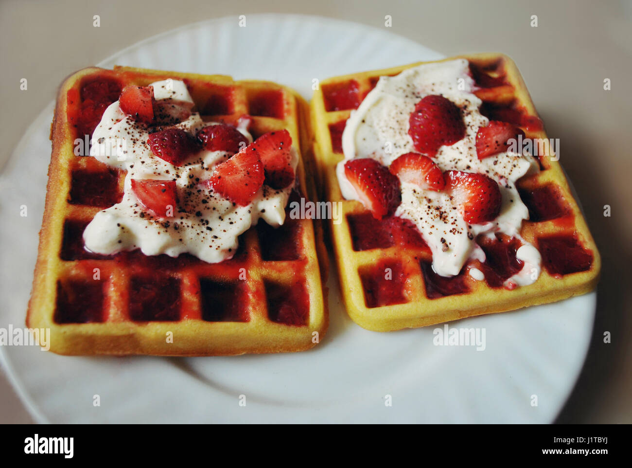 Deliziosi waffles fatti in casa con panna montata, marmellata, cacao e fragole. Foto Stock