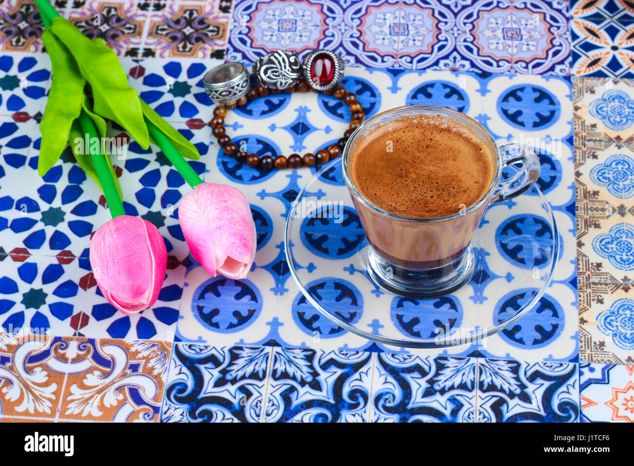 Tazza di caffè arabico su un Orientale sfondo colorato / tazza di espresso su una orientale colorato con fiori, anelli e Tamr date Foto Stock