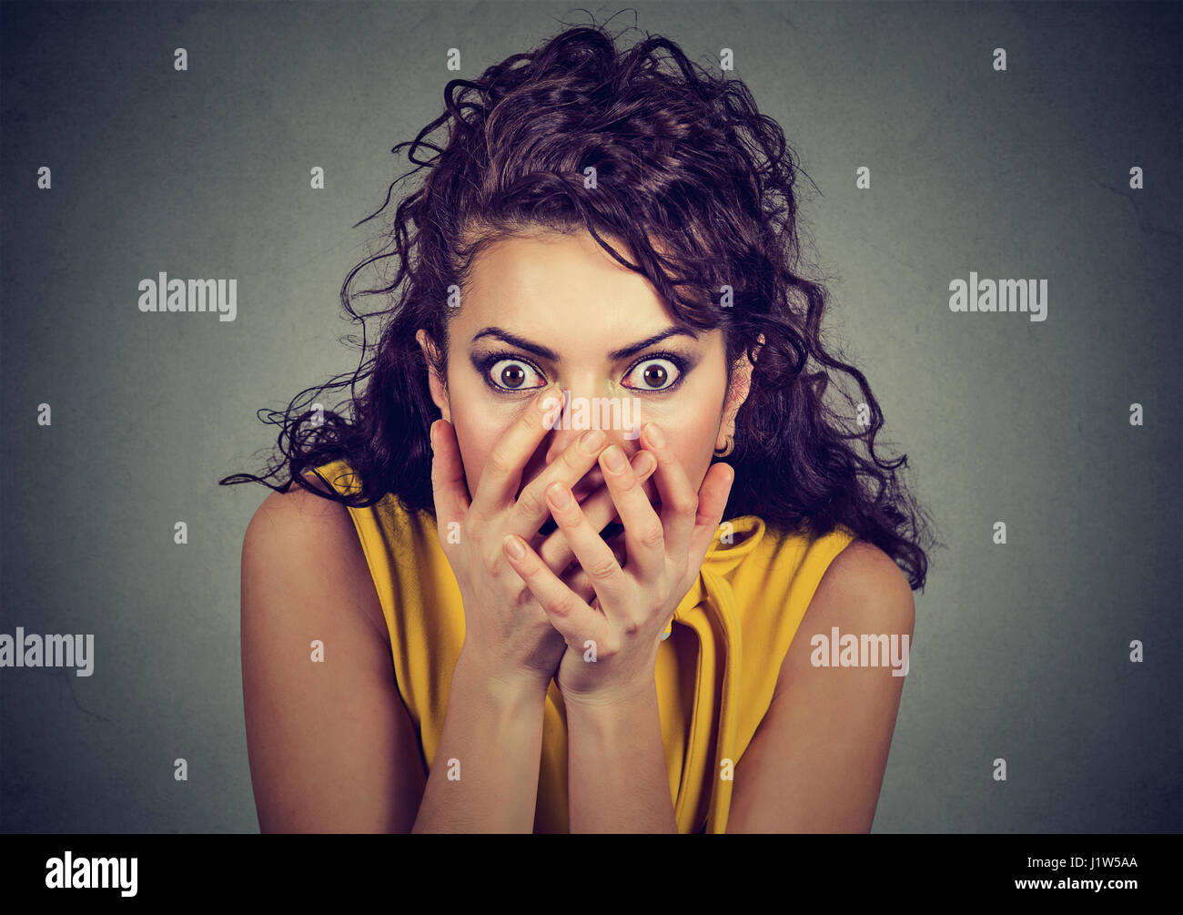 Spaventata scioccato donna con le mani sopra la sua bocca isolati su sfondo grigio Foto Stock