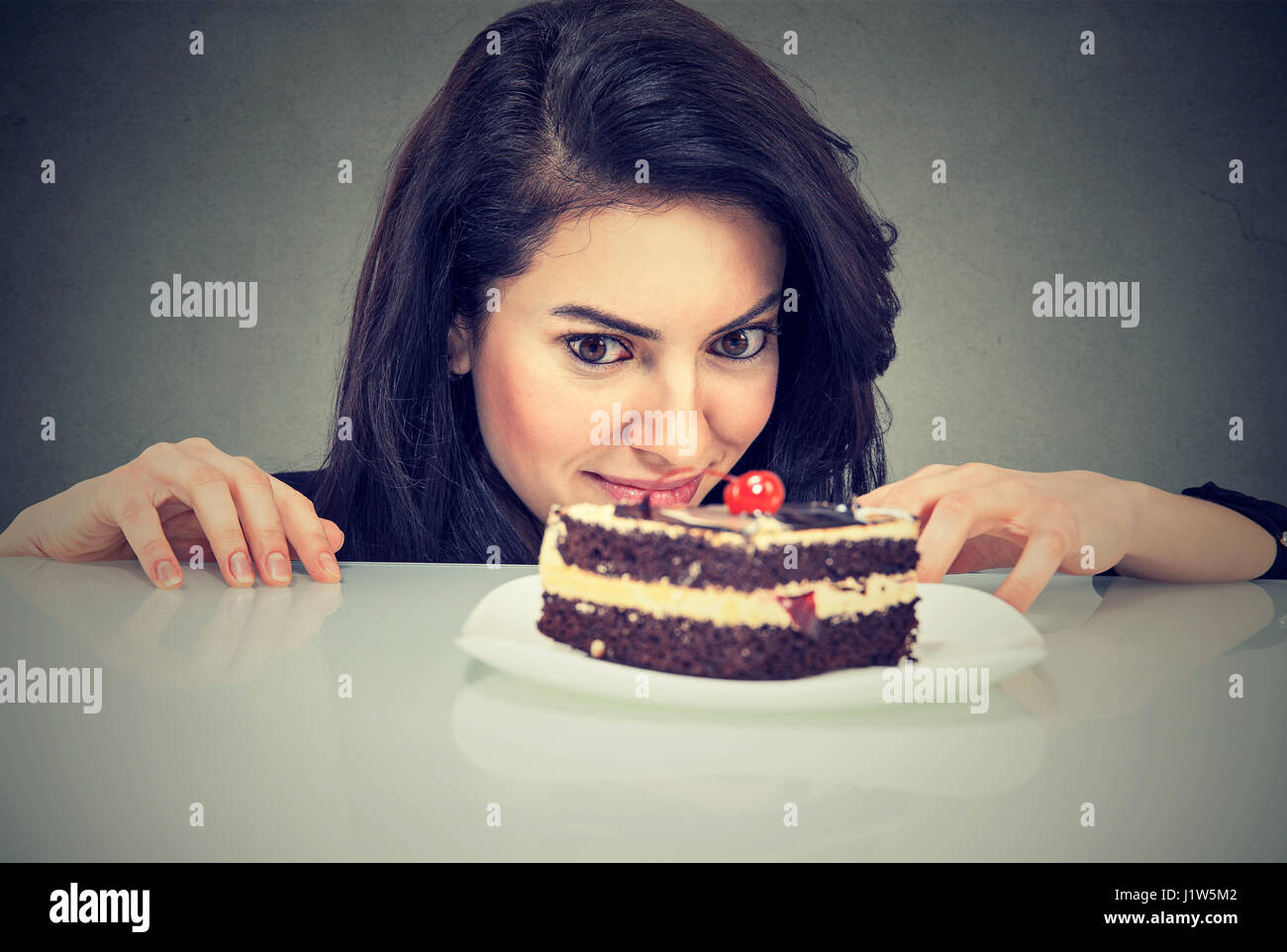 Donna craving dessert torta, desiderosi di mangiare, isolata su uno sfondo grigio Foto Stock