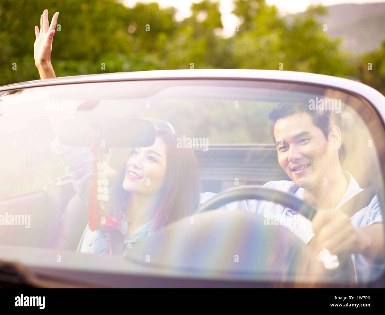 Giovani asiatici giovane godendo di un giro in cabrio auto sportiva. Foto Stock