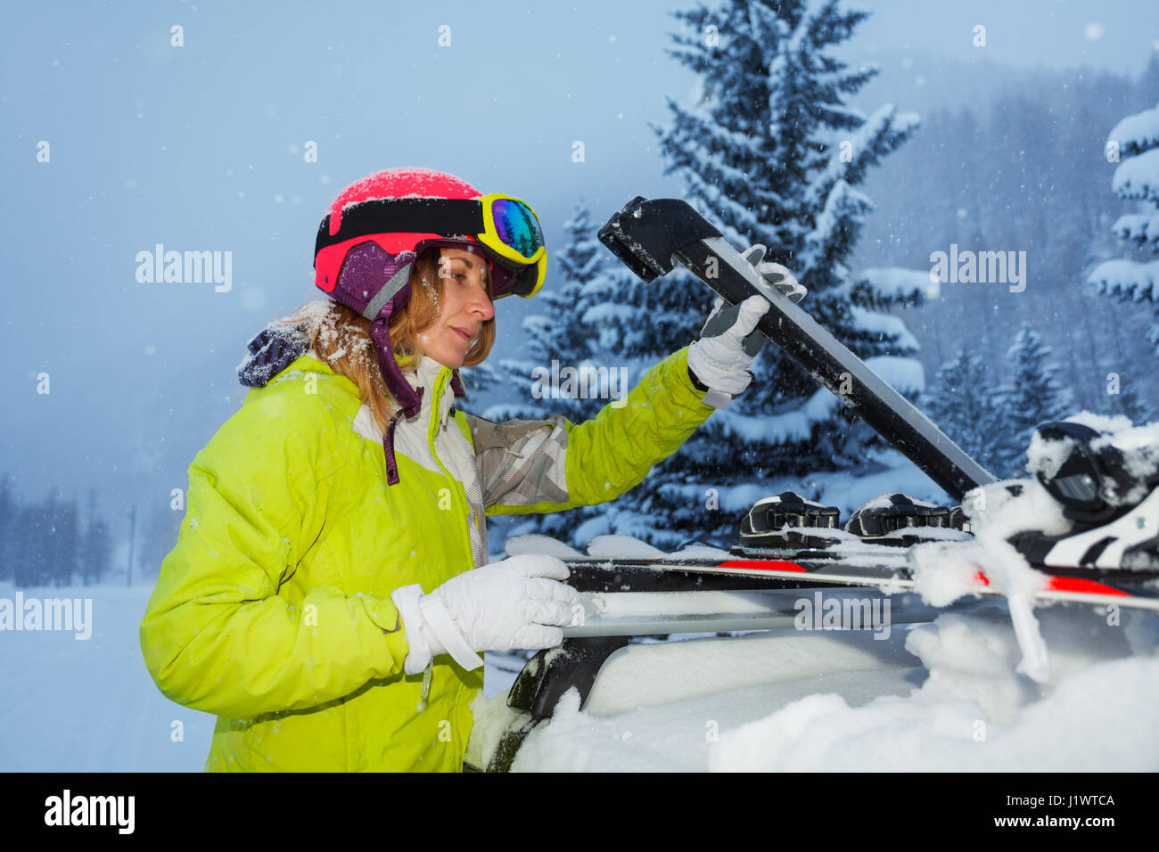 Giovane donna sci di fissaggio sul tetto della vettura dopo il viaggio di sci di montagna Foto Stock