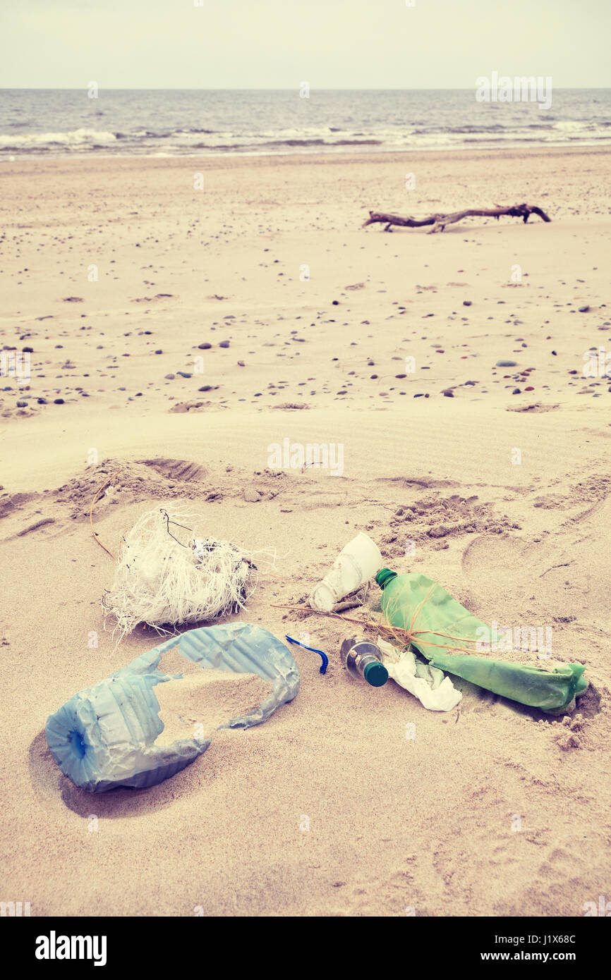 Vintage foto dai toni di immondizia a sinistra su una spiaggia, inquinamento ambientale concetto immagine. Foto Stock