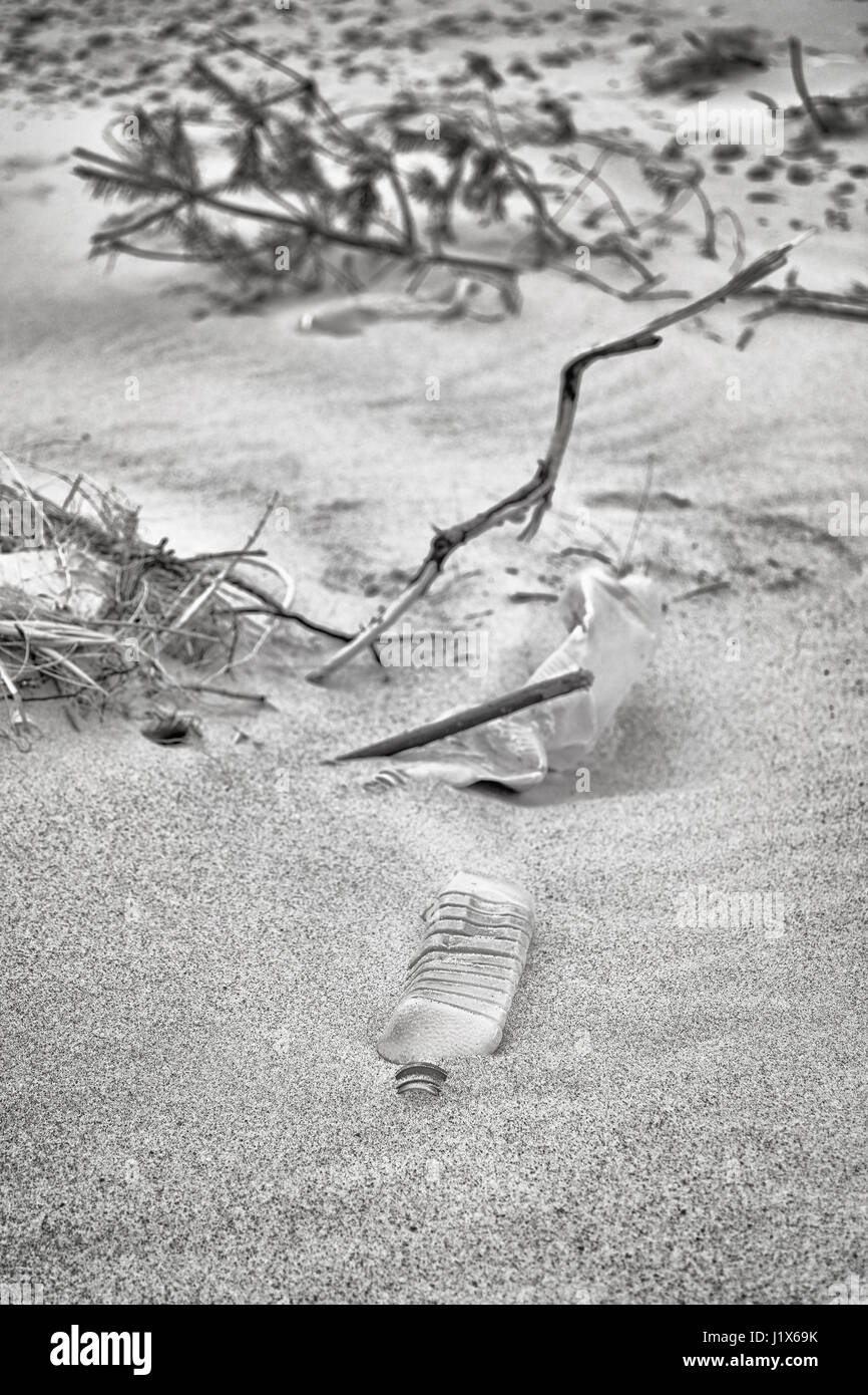 Immagine in bianco e nero di bottiglie di plastica a sinistra su una spiaggia, il fuoco selettivo, inquinamento ambientale concetto immagine. Foto Stock