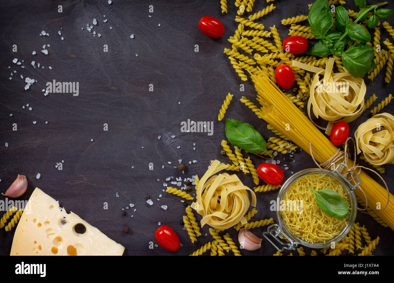 Ingredienti per la pasta italiana La cucina - spaghetti, i fusilli, le fettuccine, basilico, cherry pomodoro, aglio, pepe e formaggio. Vista da sopra con spazio per il testo. Foto Stock