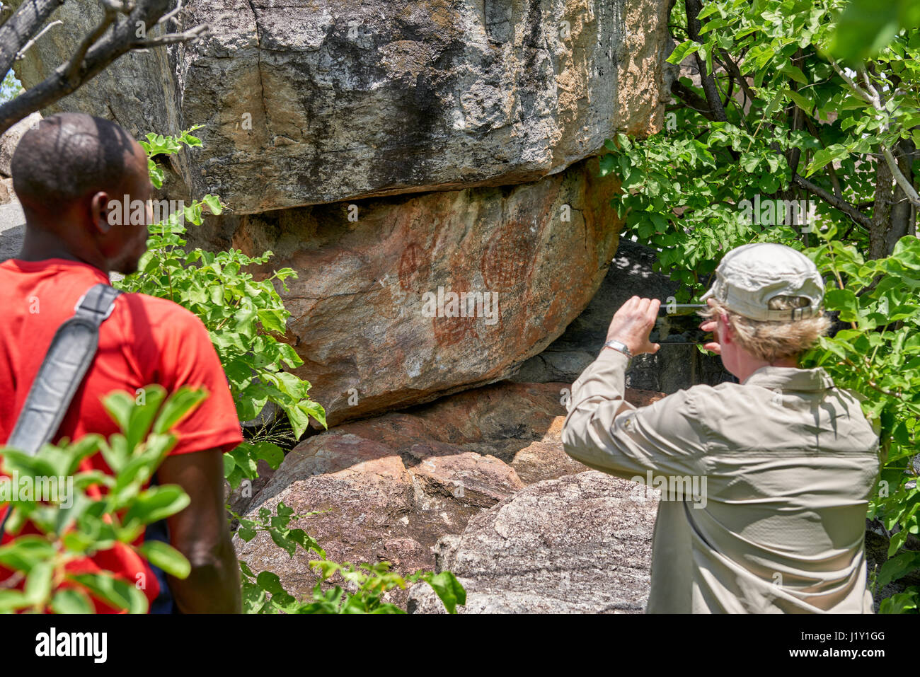 Turistiche e guide alla ricerca sull'arte rupestre, antica San dipinti, Tsodilo Hills, Botswana, Africa Foto Stock