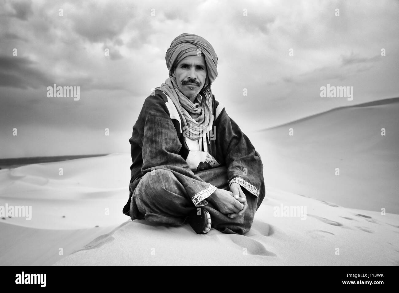 Touareg guida turistica seduto su una Duna Erg Chebbi, Marocco Foto Stock