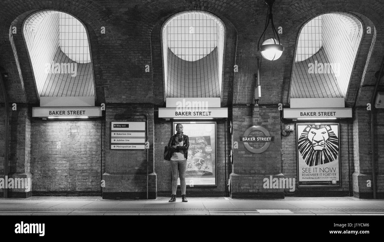 Un singolo viaggiatore femmina attende il suo tubo su piattaforma in London Baker Street Underground / Stazione della metropolitana. Foto Stock