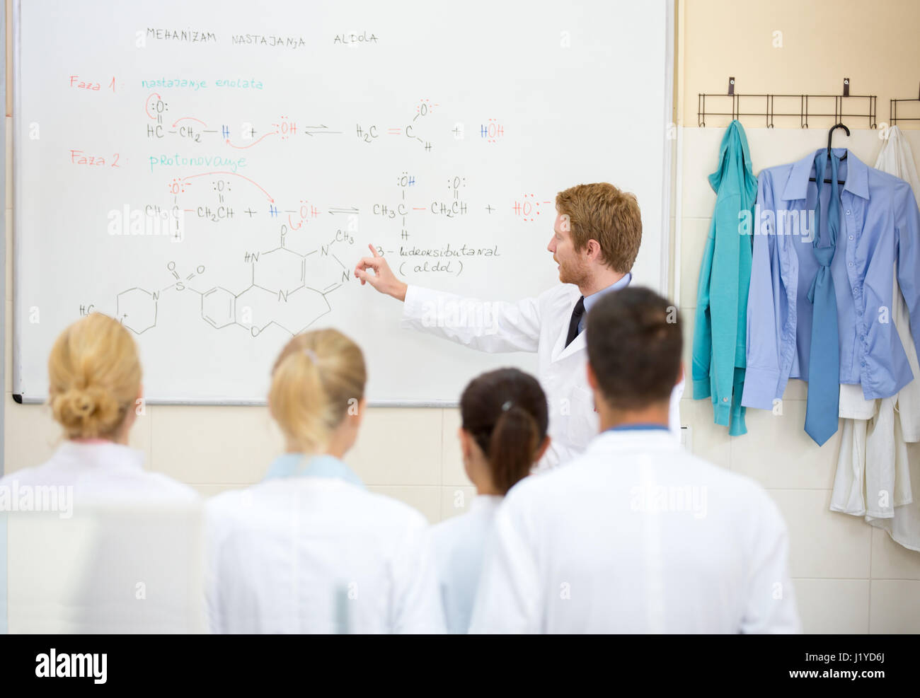 Giovane maschio insegnante di chimica spiegare la lezione per i suoi studenti di fronte di Blackboard Foto Stock