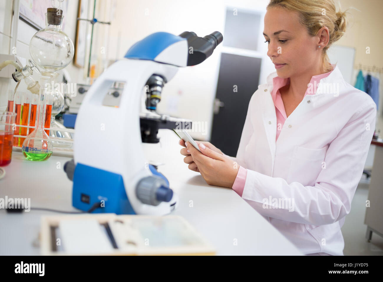 Femmina lavoratore laboratorio cercare dati chimici a ipod in laboratorio Foto Stock