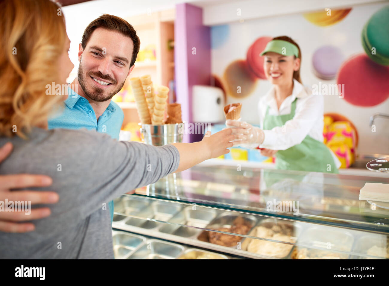 Uomo sorridente comprare gelati la sua ragazza nel negozio di pasticceria Foto Stock