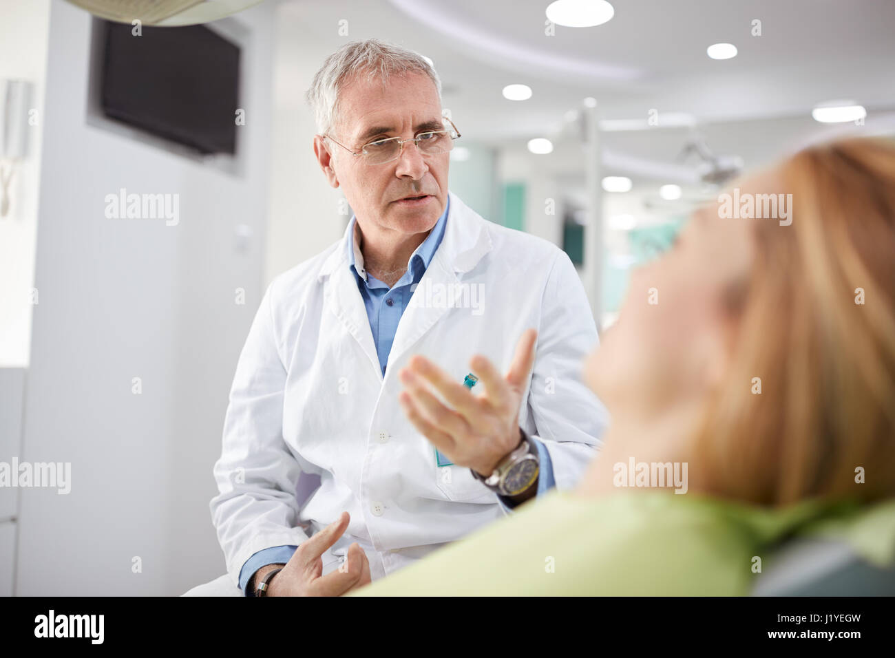 Dentista maschio sul posto di lavoro con il paziente di sesso femminile in pratica dentistica Foto Stock