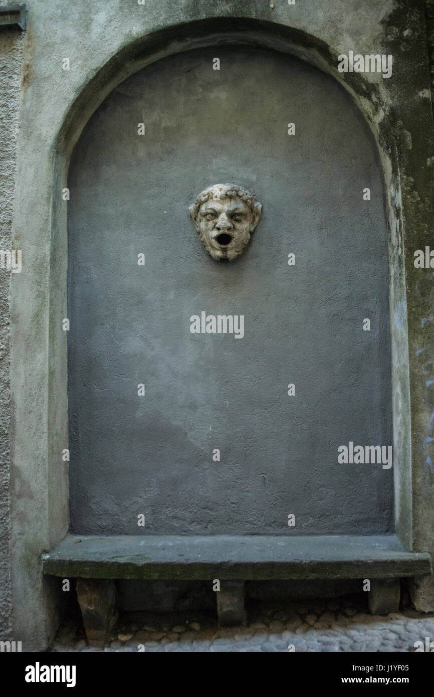 Pietra figura del viso e panca incassato in una parete del giardino, la Città Alta di Bergamo, Italia Foto Stock