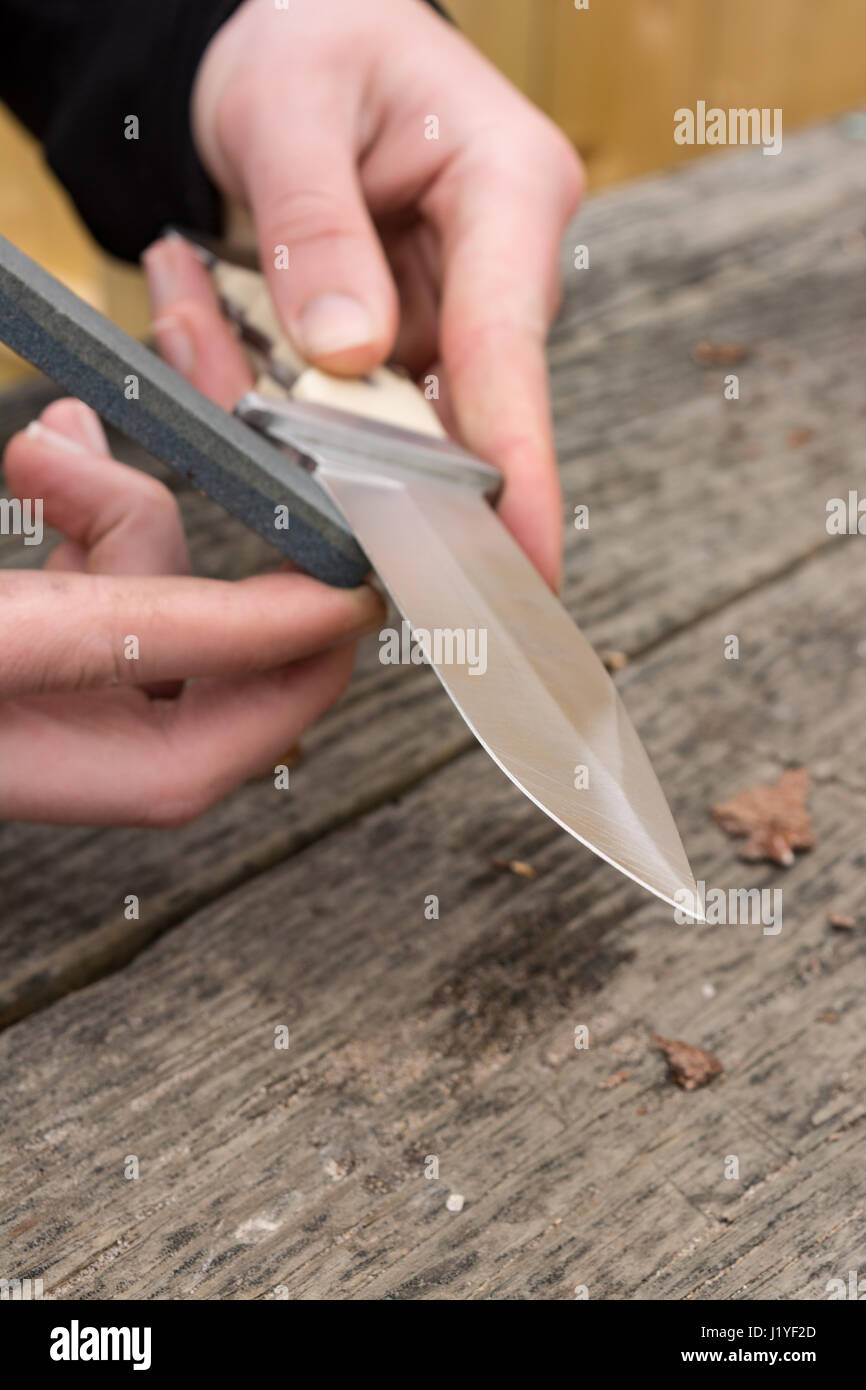 Maschio di mani grandi di affilatura coltelli da tasca con una