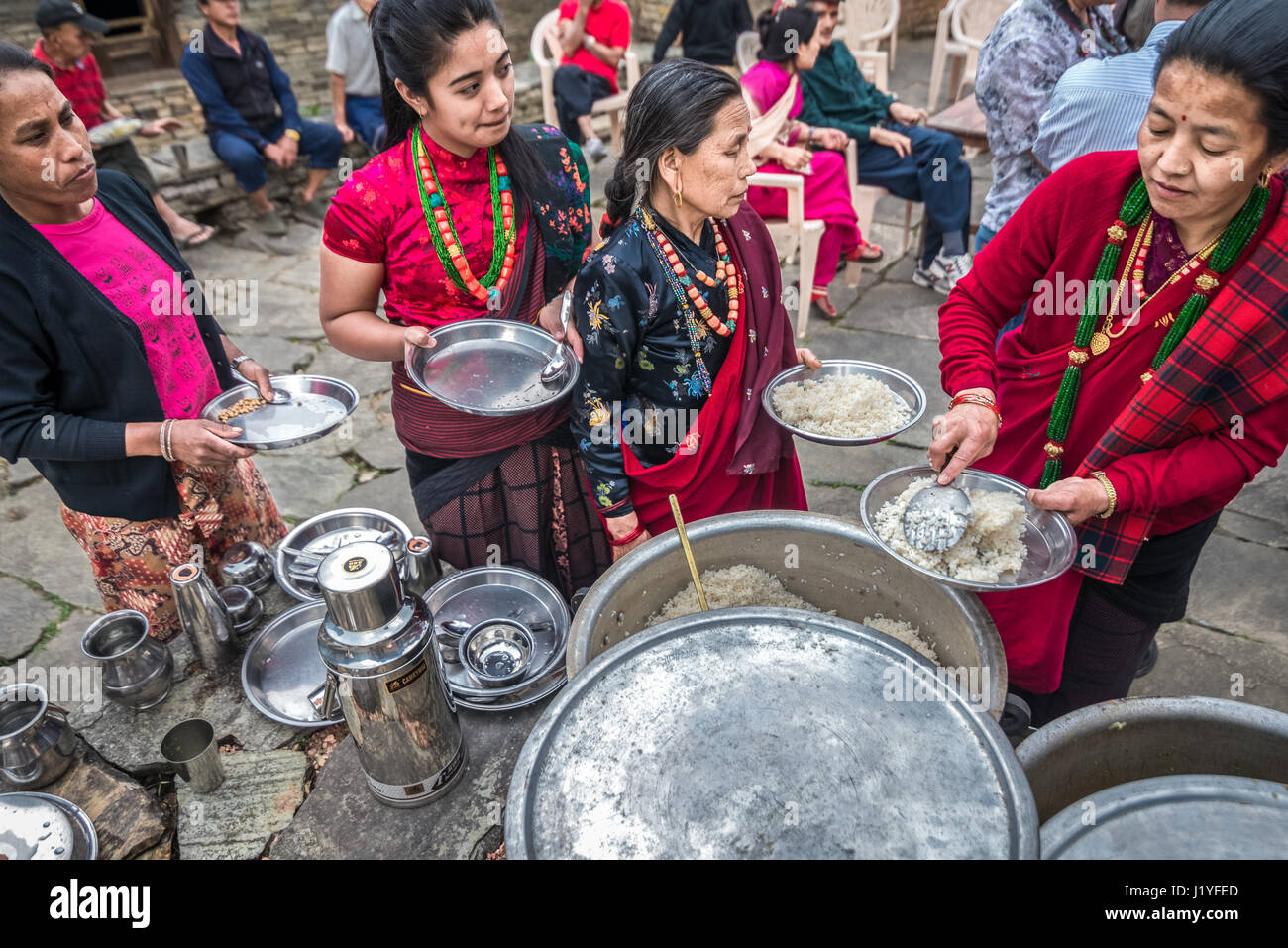 Le donne nei tradizionali costumi Gurung avente alimenti durante una celebrazione locale nel villaggio Sidhane, Kaski, Nepal. Foto Stock