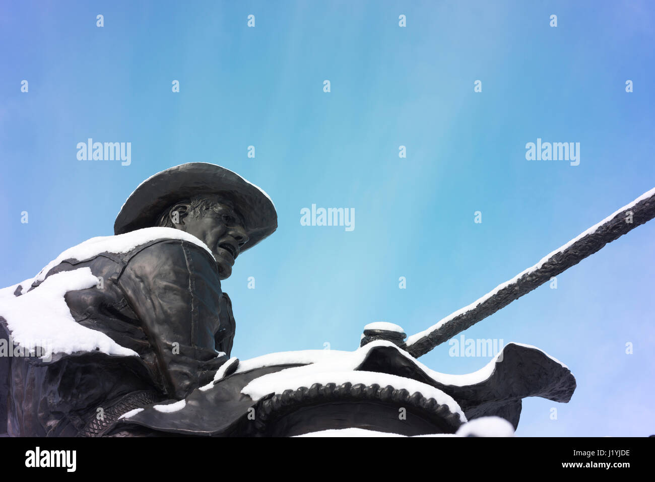 Cowboy omaggio statua di un cowboy a cavallo con la neve. Foto Stock