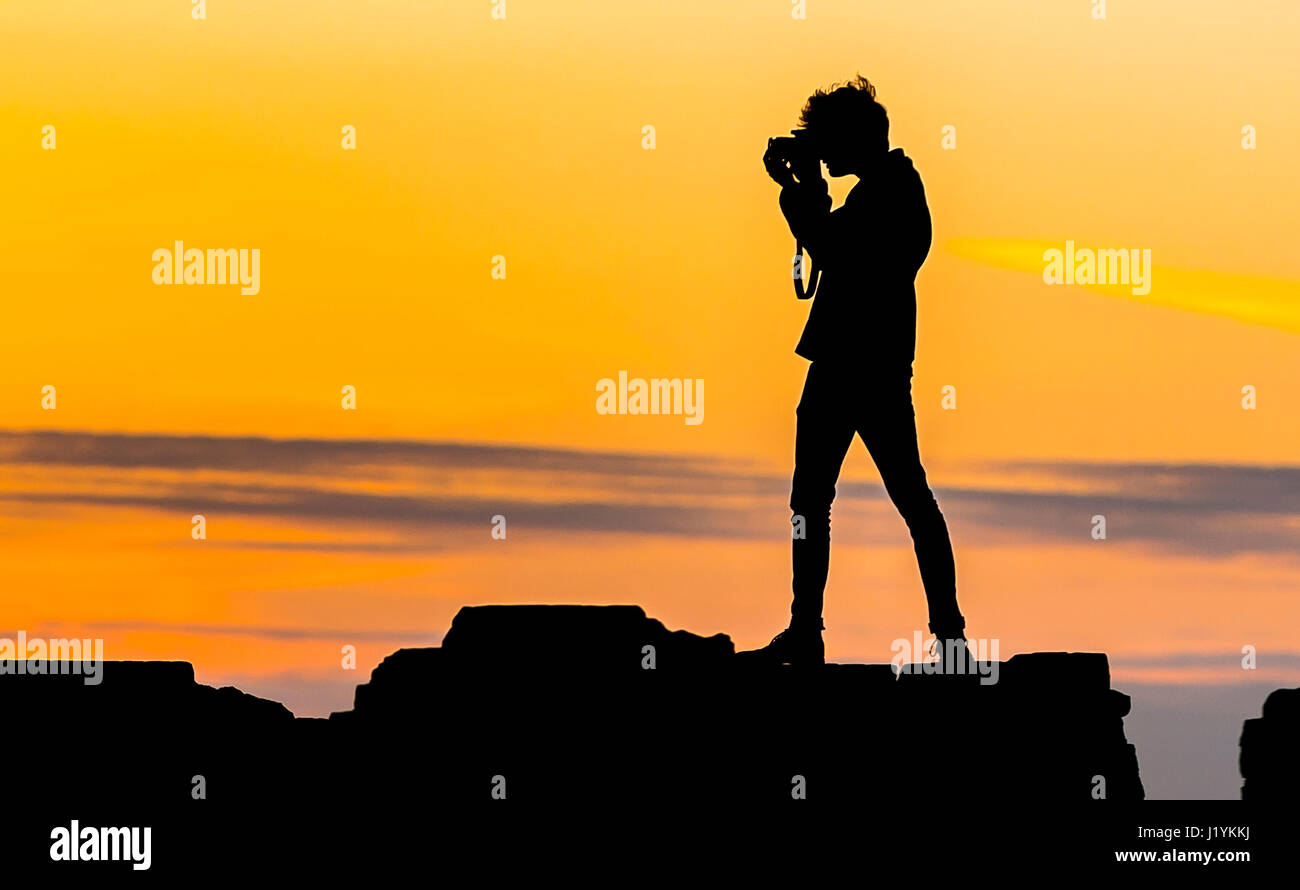 Fotografo di sera. Silhouette di un giovane fotografo di scattare le foto con una fotocamera a tarda sera quando il sole tramonta. Foto Stock