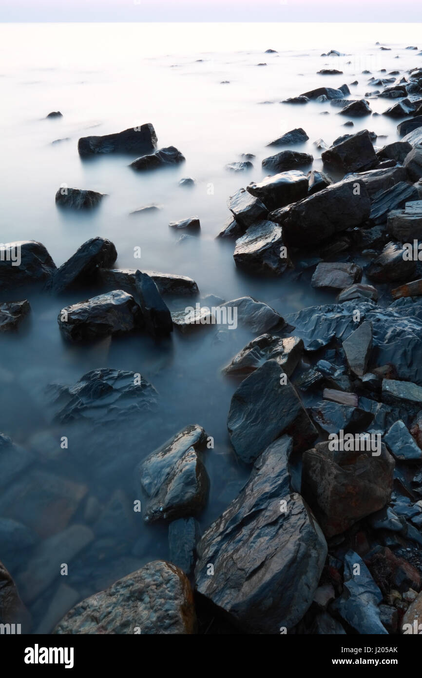 Un paesaggio della costa del Mar Nero con grandi pietre e acqua calma superficie al crepuscolo Foto Stock