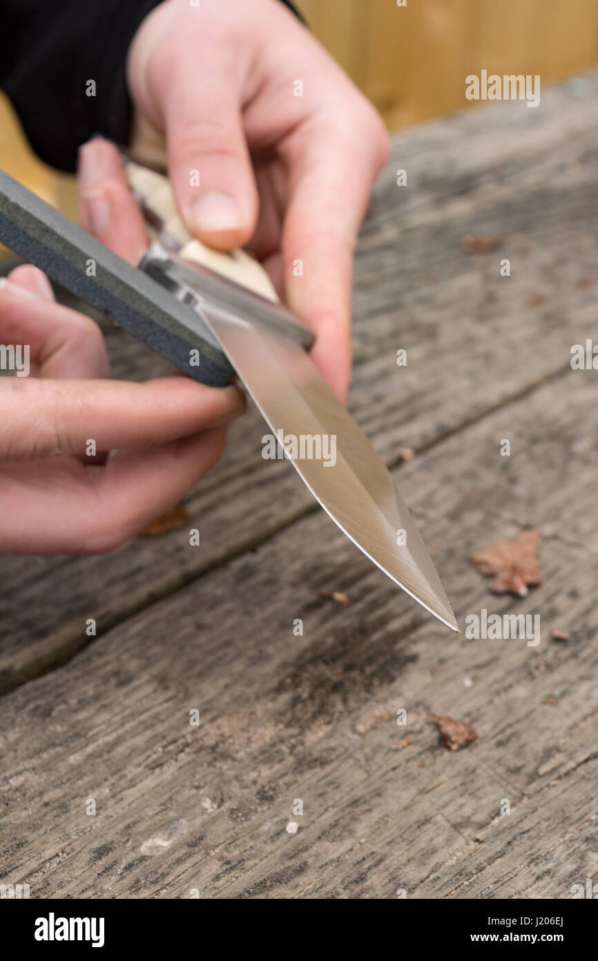 Maschio di mani grandi di affilatura coltelli da tasca con una pietra  abrasiva Foto stock - Alamy