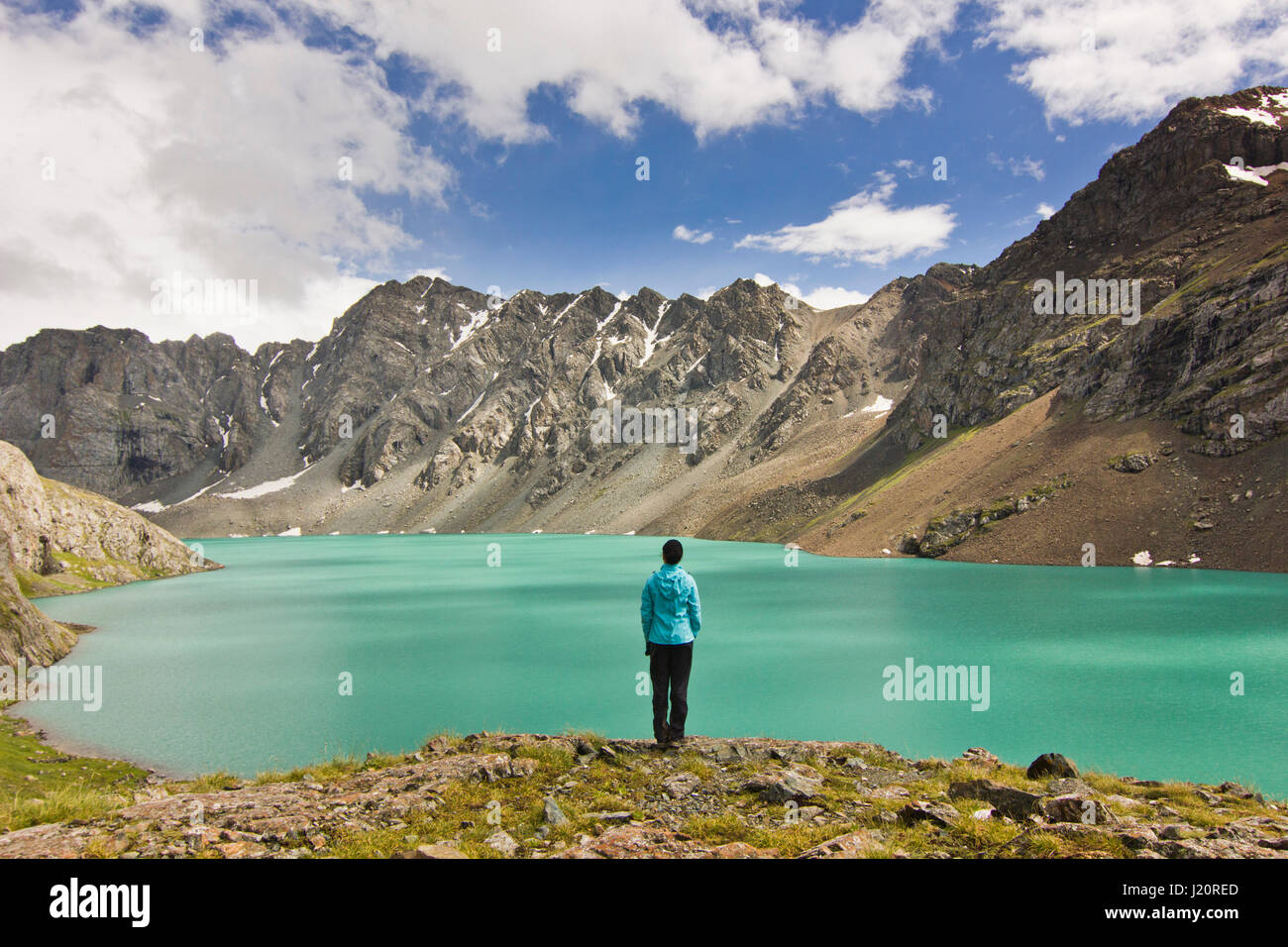 Ragazza in giacca blu in piedi sopra la calma blue mountain lake Alakol con montagne circondate Foto Stock