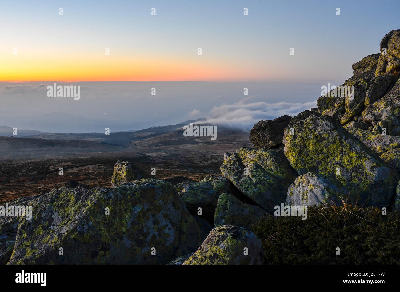 Tramonto in montagna sopra le nuvole con spazio di copia e la pila di rocce Foto Stock