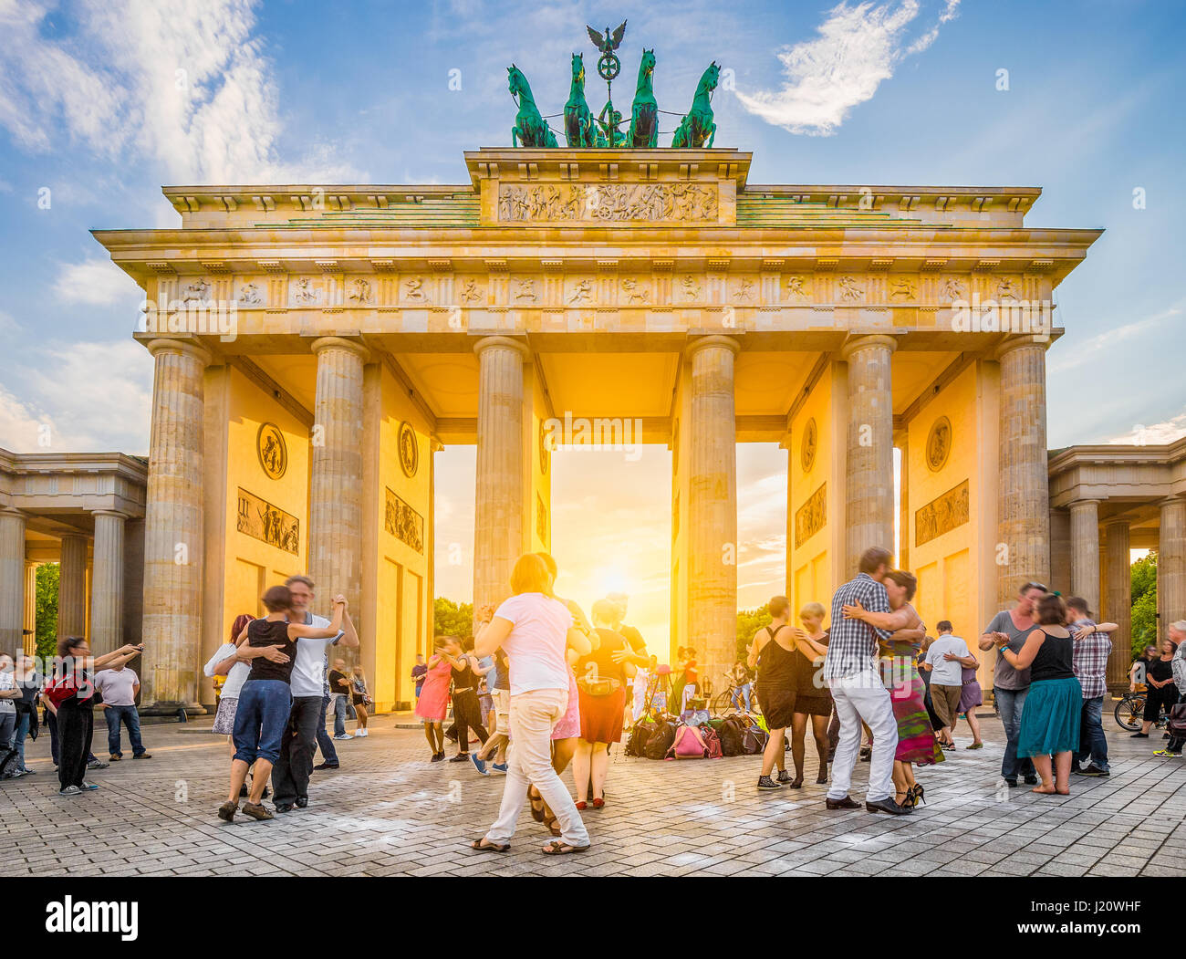 La gente ballare nella parte anteriore della famosa Porta di Brandeburgo, un simbolo di pace e di unità e punto di riferimento storico, in golden luce della sera al tramonto, Berlino Foto Stock