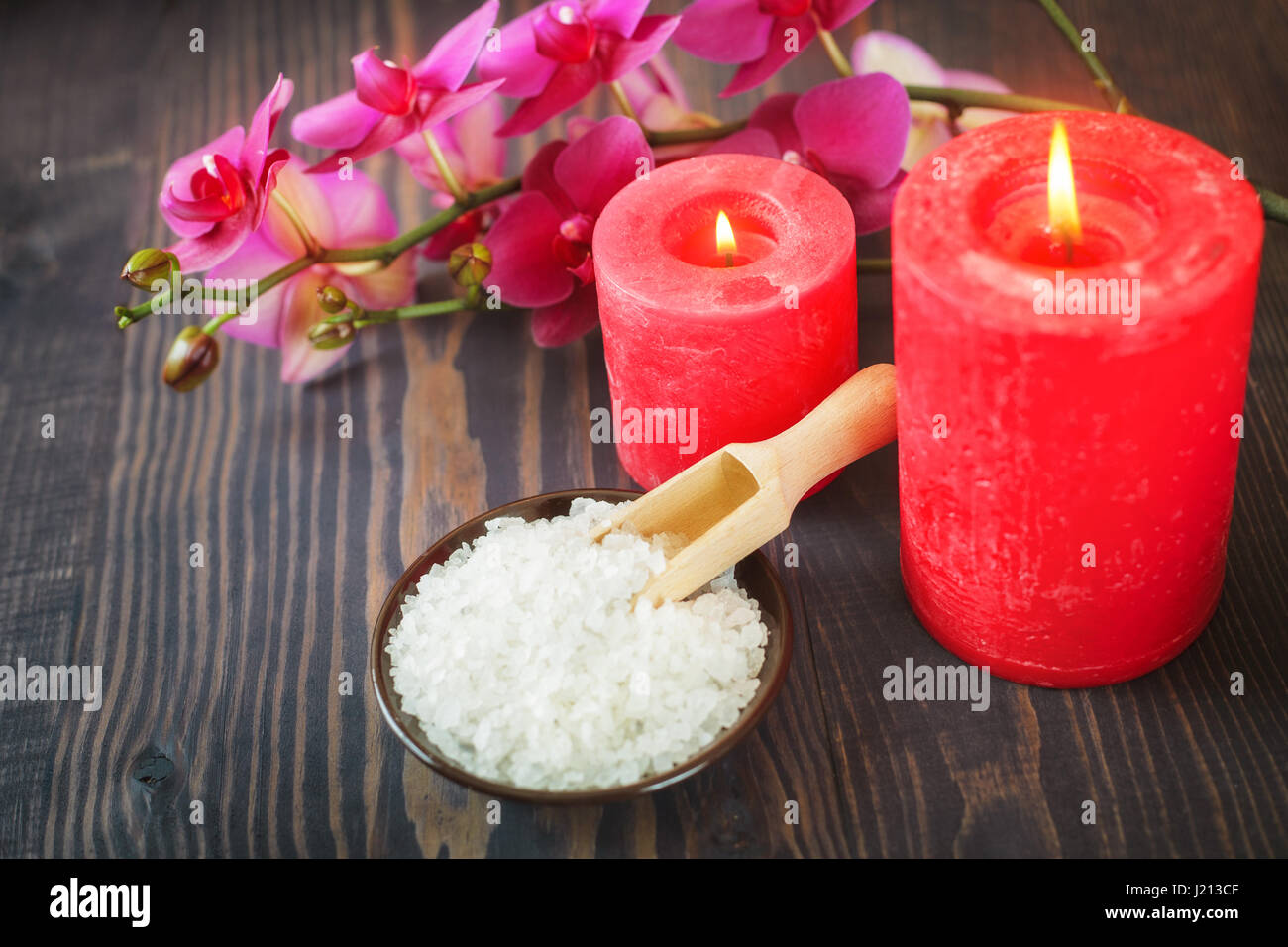 Bagno di mare sale, candele e fiori su un sfondo di legno. Il concetto di relax e trattamenti termali. Foto Stock