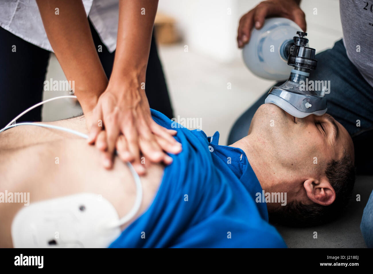 Una ragazza aiutando un ragazzo dopo un attacco di cuore con la rianimazione cardiopolmonare Foto Stock