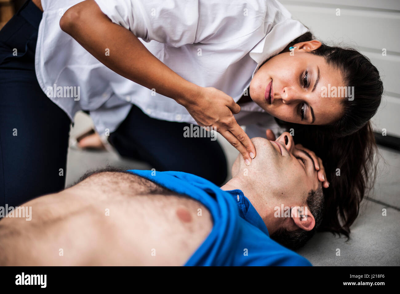 Una ragazza aiutando un ragazzo dopo un attacco di cuore con la rianimazione cardiopolmonare Foto Stock